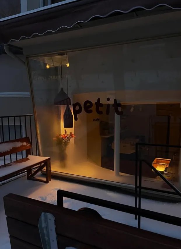 Eckladen von Café Petit am Abend mit beleuchtetem Schriftzug